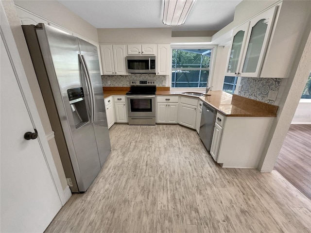 kitchen featuring appliances with stainless steel finishes, white cabinetry, sink, and light hardwood / wood-style flooring