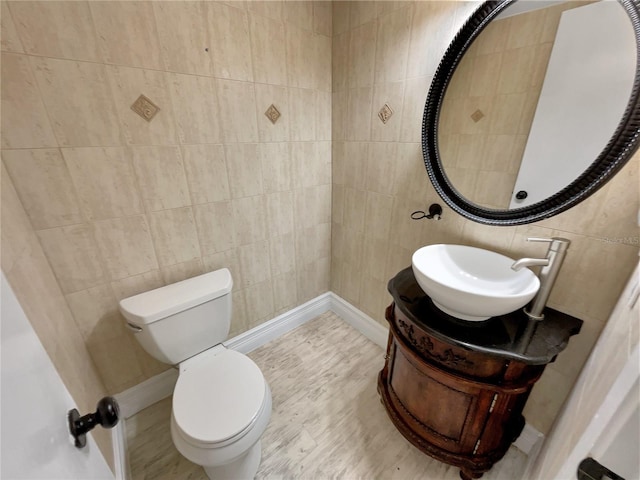 bathroom featuring tile walls, wood-type flooring, vanity, and toilet