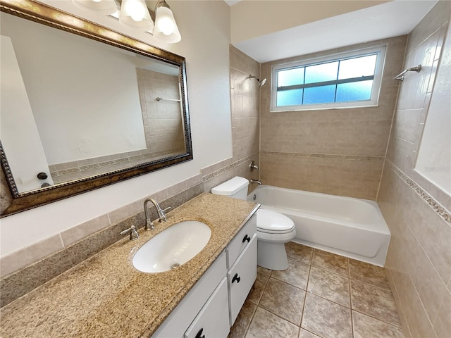 full bathroom with tiled shower / bath, vanity, toilet, tile walls, and tile patterned flooring