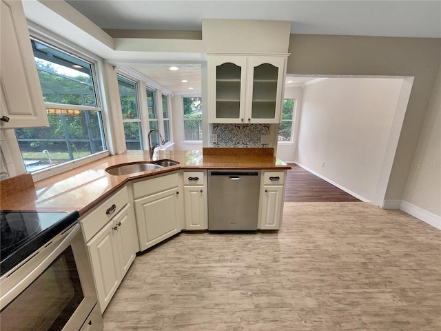 kitchen featuring tasteful backsplash, sink, white cabinetry, light hardwood / wood-style flooring, and stainless steel appliances