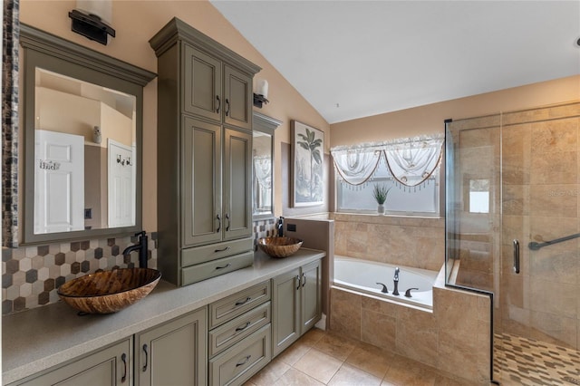 bathroom featuring vanity, vaulted ceiling, tile patterned flooring, shower with separate bathtub, and tasteful backsplash