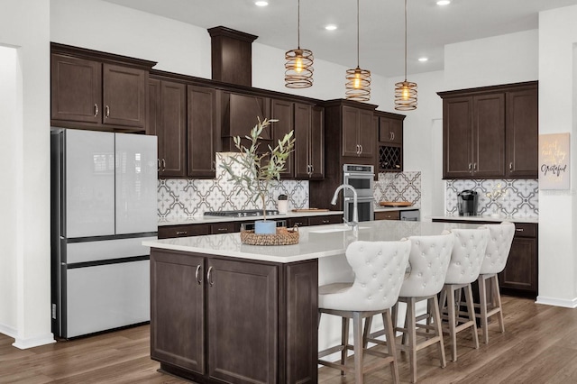 kitchen featuring decorative backsplash, white refrigerator, dark hardwood / wood-style floors, and a center island with sink