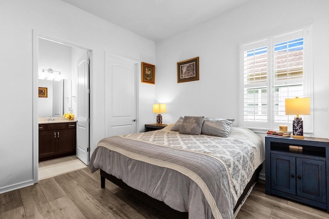 bedroom with light hardwood / wood-style floors, a closet, and ensuite bath