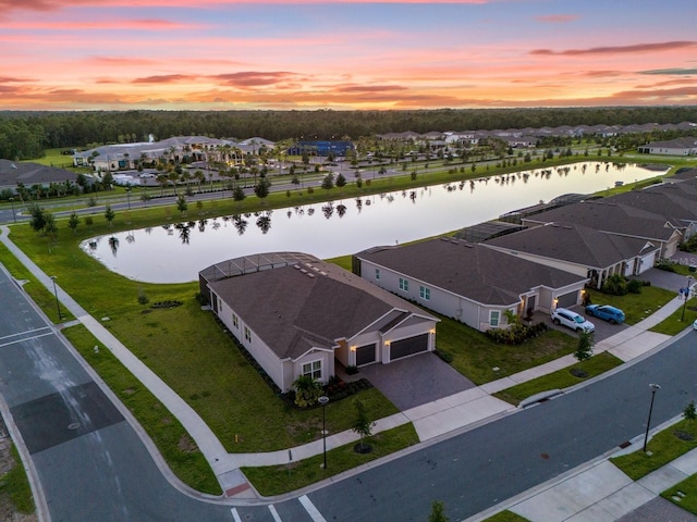 aerial view at dusk featuring a water view