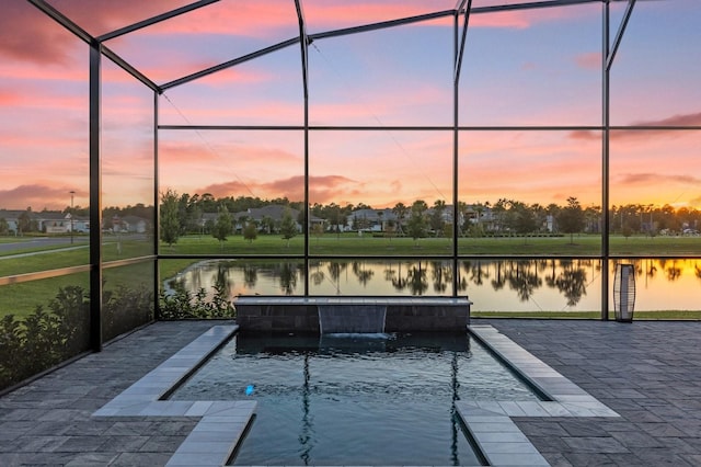 pool at dusk with a lanai, a water view, and a patio