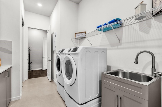 laundry room featuring cabinets, washing machine and dryer, light tile patterned floors, and sink