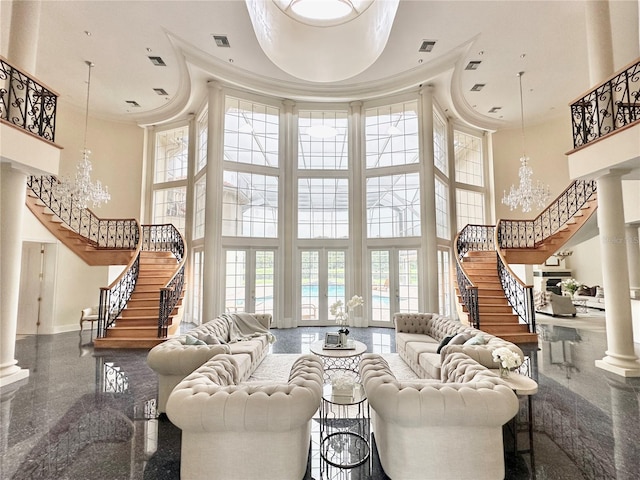 living room with decorative columns, a towering ceiling, a chandelier, and a wealth of natural light