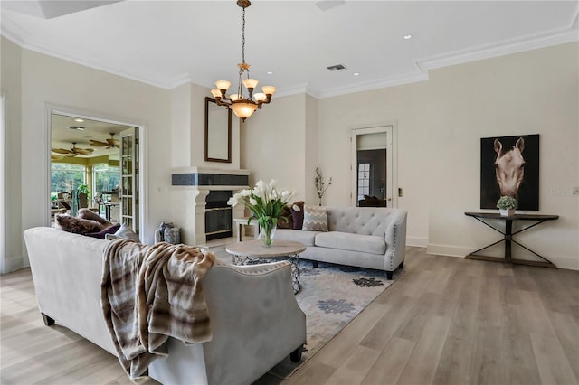 living room featuring a notable chandelier, light hardwood / wood-style flooring, and crown molding