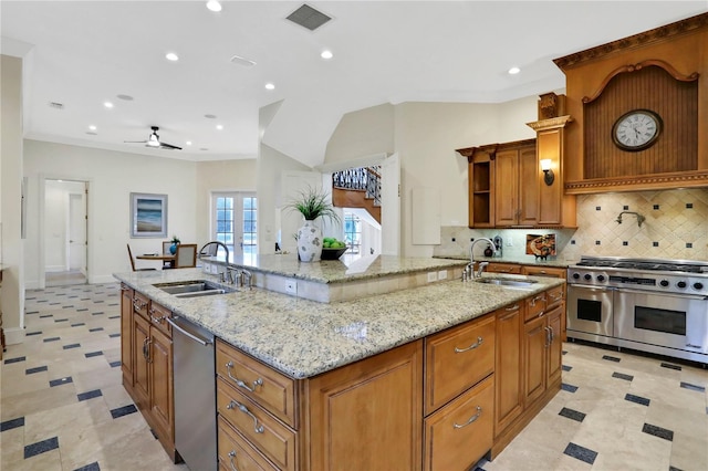 kitchen with ceiling fan, an island with sink, appliances with stainless steel finishes, and sink