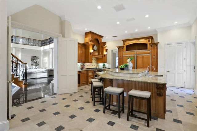 kitchen with a breakfast bar, tasteful backsplash, a large island with sink, sink, and premium appliances