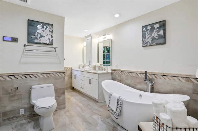 bathroom featuring tile walls, a washtub, vanity, and toilet