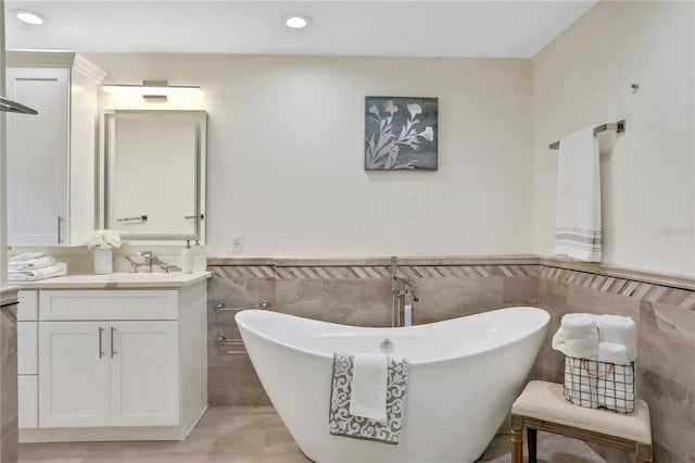 bathroom featuring a bathing tub, vanity, and tile walls