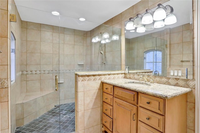 bathroom with vanity, tile walls, a shower with shower door, and decorative backsplash