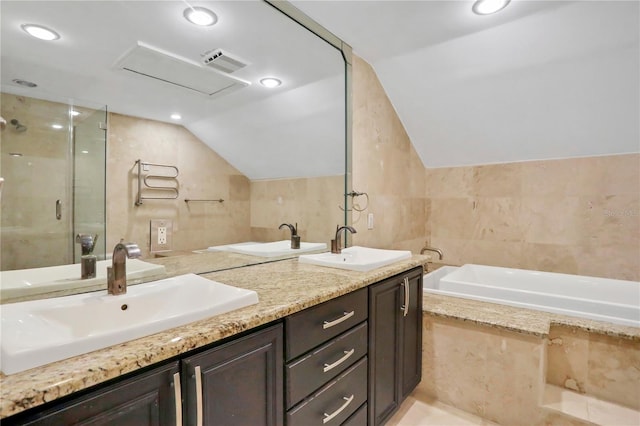 bathroom with tile walls, lofted ceiling, vanity, and plus walk in shower