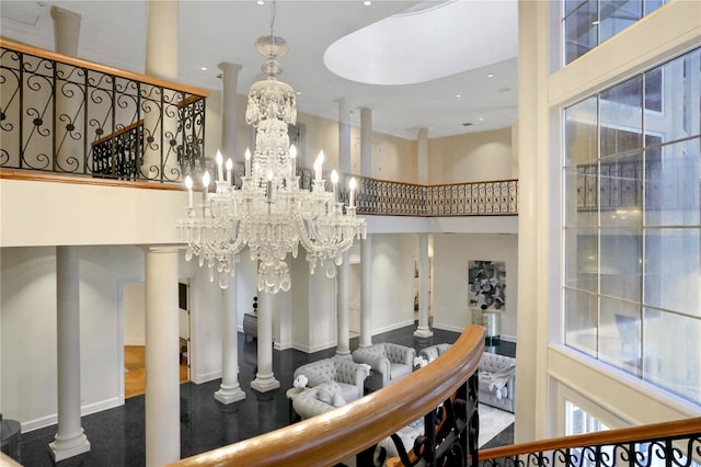 stairs with a notable chandelier, a towering ceiling, and decorative columns