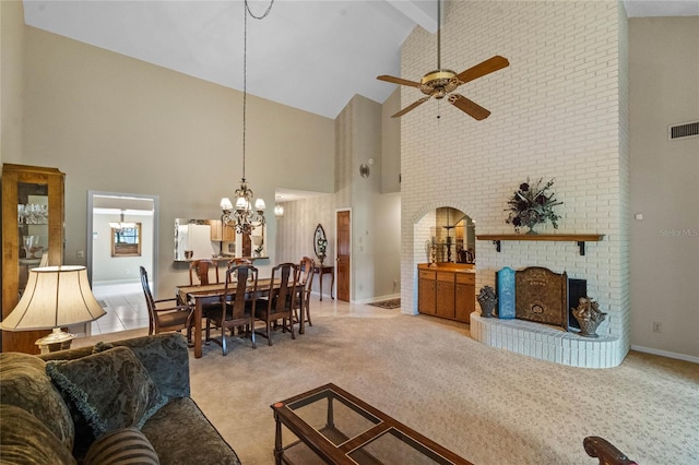 carpeted living room featuring ceiling fan with notable chandelier, a fireplace, beamed ceiling, and high vaulted ceiling