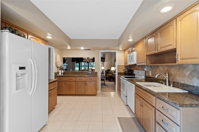 kitchen featuring light tile patterned floors, sink, white appliances, tasteful backsplash, and dark stone countertops