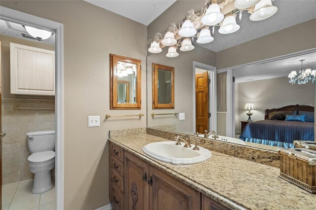 bathroom featuring vanity, a textured ceiling, tile patterned floors, tile walls, and toilet