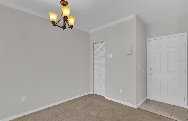 spare room with crown molding, a notable chandelier, and carpet flooring