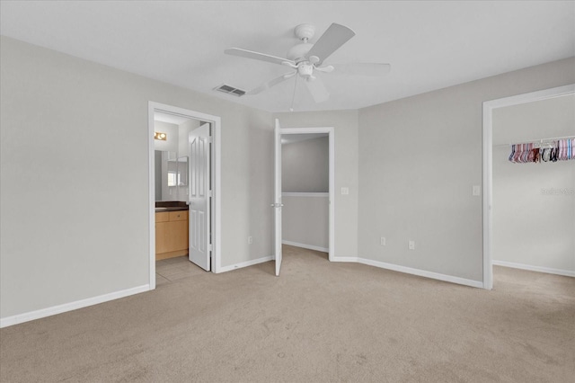 unfurnished bedroom featuring a closet, ceiling fan, light carpet, and ensuite bath