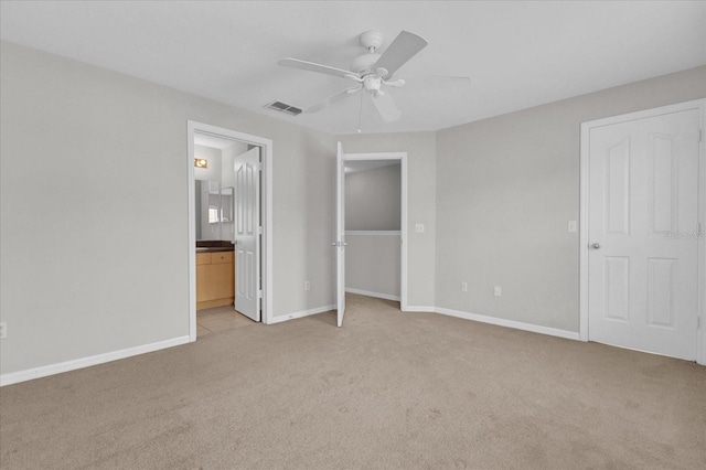 unfurnished bedroom featuring ceiling fan, light colored carpet, and connected bathroom