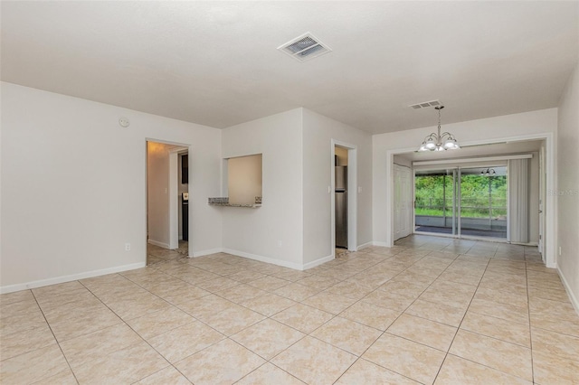 tiled empty room with an inviting chandelier