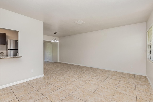 tiled spare room featuring a chandelier