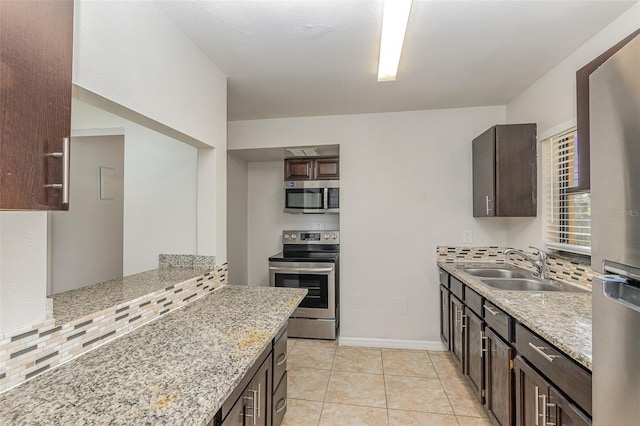 kitchen featuring light stone counters, tasteful backsplash, sink, appliances with stainless steel finishes, and dark brown cabinetry