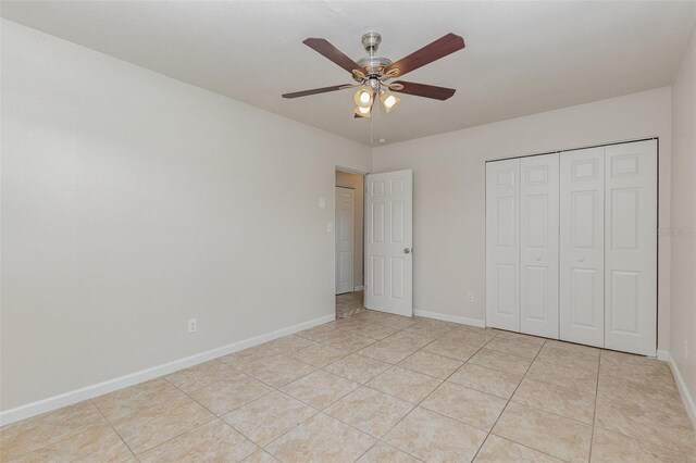 unfurnished bedroom with light tile patterned flooring, ceiling fan, and a closet