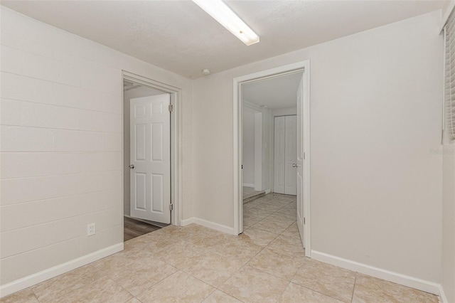 tiled empty room featuring a textured ceiling