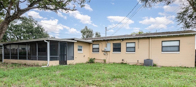 back of house featuring a sunroom, a lawn, and central AC