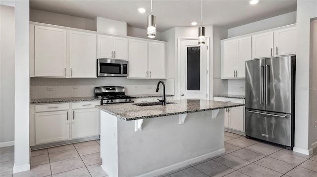 kitchen featuring sink, a kitchen island with sink, white cabinetry, stainless steel appliances, and dark stone countertops