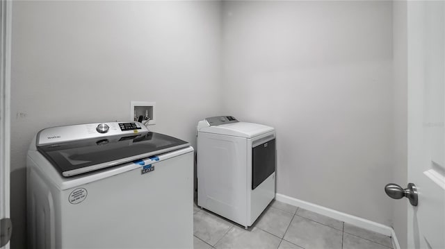 clothes washing area with light tile patterned floors and independent washer and dryer