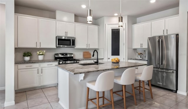 kitchen with stainless steel appliances, an island with sink, sink, and white cabinetry