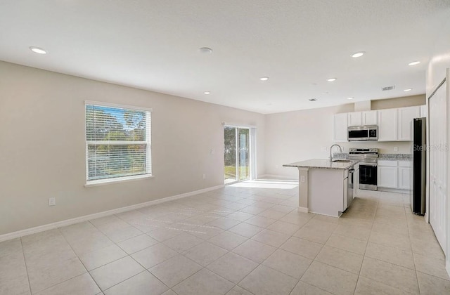 kitchen featuring light stone counters, white cabinets, sink, a kitchen island with sink, and stainless steel appliances