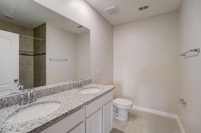 bathroom with a tile shower, tile patterned floors, vanity, and toilet