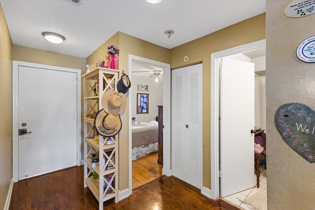 hall with a textured ceiling and dark hardwood / wood-style flooring