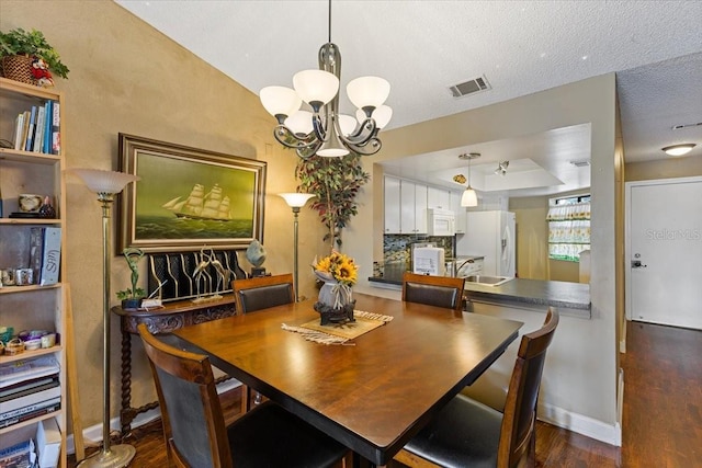 dining space with an inviting chandelier, dark hardwood / wood-style flooring, and a textured ceiling