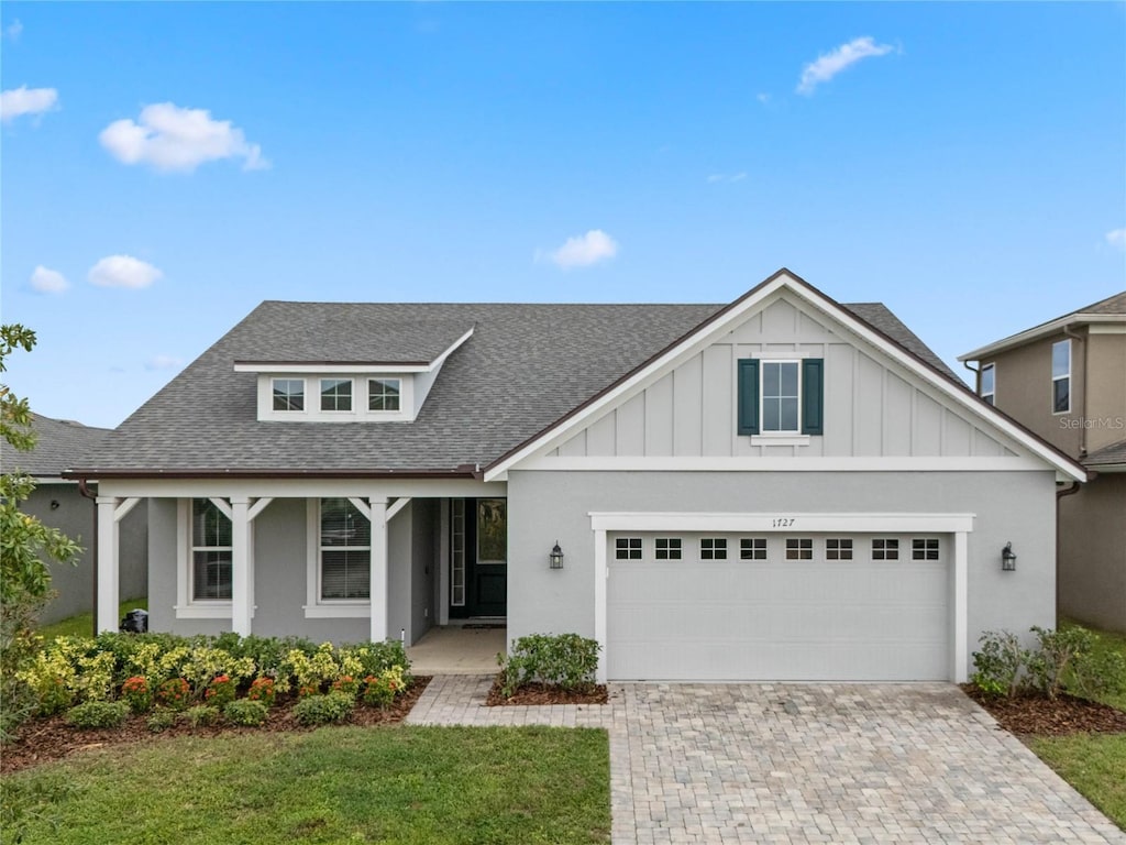 view of front of house featuring a front yard, a porch, and a garage