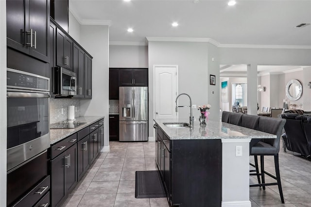 kitchen featuring sink, a center island with sink, appliances with stainless steel finishes, a breakfast bar area, and crown molding