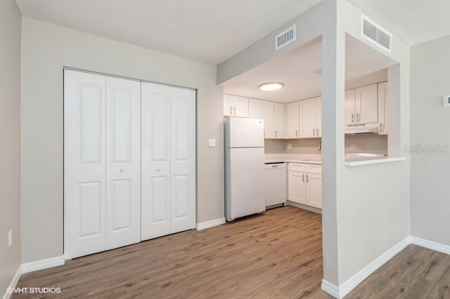 kitchen featuring light wood-type flooring, white appliances, and white cabinets