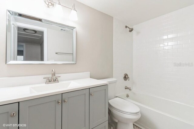 full bathroom featuring vanity, tiled shower / bath combo, and toilet