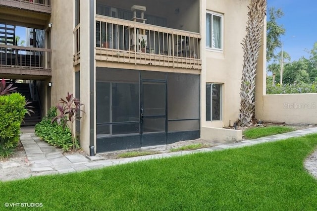 back of house with a lawn and a balcony