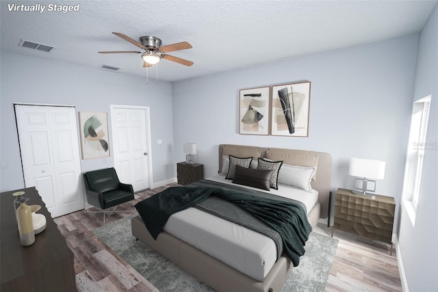 bedroom featuring ceiling fan, hardwood / wood-style floors, and a textured ceiling