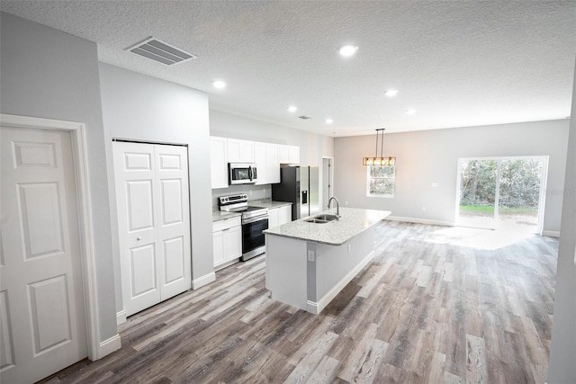 kitchen featuring white cabinets, a center island with sink, stainless steel appliances, and sink