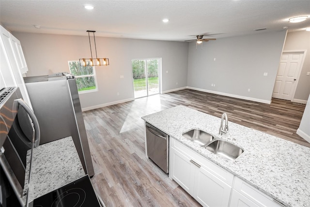 kitchen with vaulted ceiling, white cabinets, light stone countertops, stainless steel dishwasher, and sink