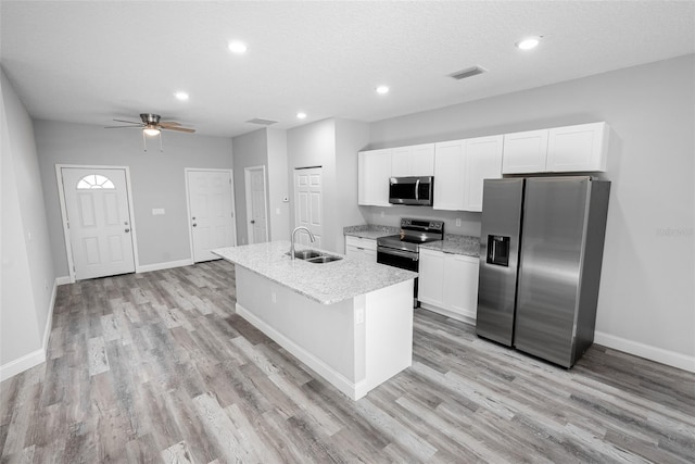 kitchen featuring light hardwood / wood-style floors, an island with sink, white cabinetry, stainless steel appliances, and ceiling fan