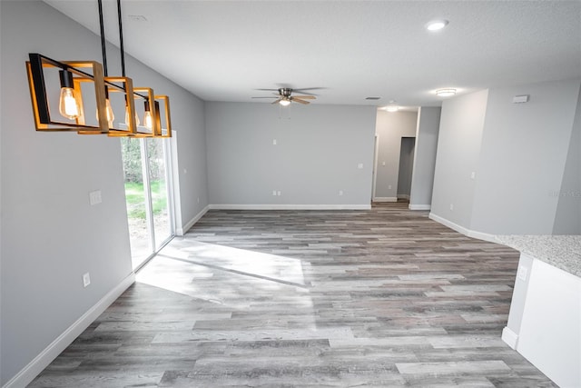 spare room featuring ceiling fan with notable chandelier and light hardwood / wood-style floors