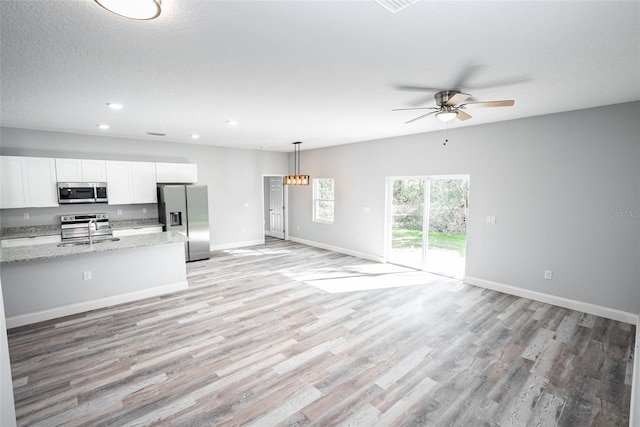 kitchen featuring sink, light hardwood / wood-style flooring, white cabinetry, appliances with stainless steel finishes, and light stone countertops