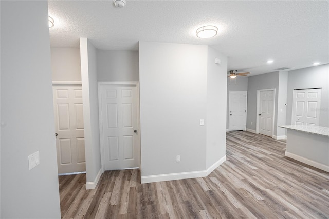 unfurnished room featuring a textured ceiling, light hardwood / wood-style floors, and ceiling fan